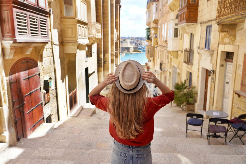 Travel Companies in France- tourism-view-tourist-girl-holding-hat-descends-stairs-old-town-valletta-unesco-world-heritage-malta